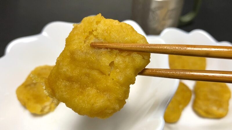 電子レンジで温めたチキンナゲットを箸で持ち上げた様子。衣がしっとりとして柔らかい印象。