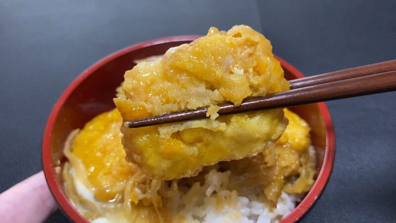ご飯の上にのせたチキンナゲットの卵とじを箸で持ち上げた様子。衣に卵がしっかり絡んでいる。