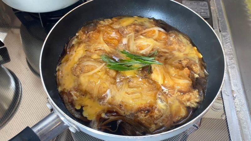 チキンナゲットを卵でとじているフライパンの様子。溶き卵と玉ねぎが混ざり、とろとろに仕上がっている。