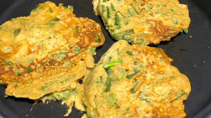 チヂミを裏返して焼いている場面。こんがりとした焼き色がつき始めている。
