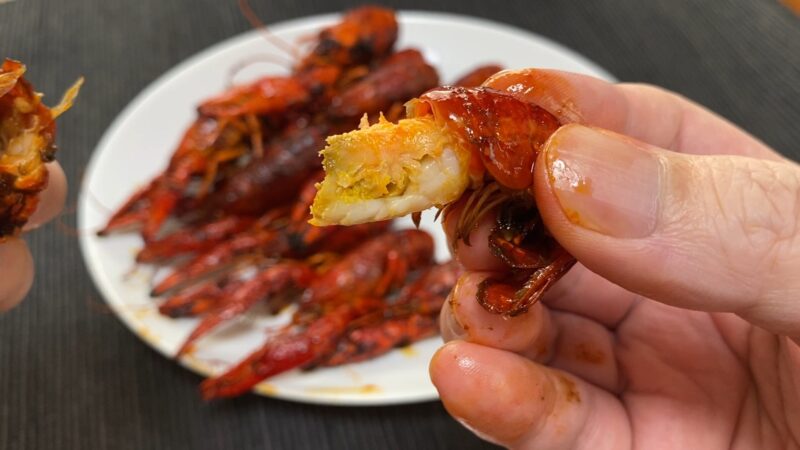 剥いたザリガニの身。中から白く柔らかい肉が現れ、黄色いみそが付着している。