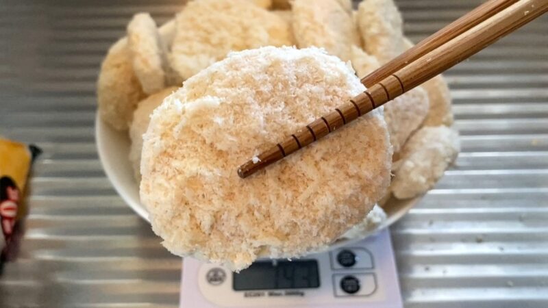 冷凍チキンカツを箸で持ち上げたクローズアップ写真。パン粉の粒立ちがよく分かるアップショット。