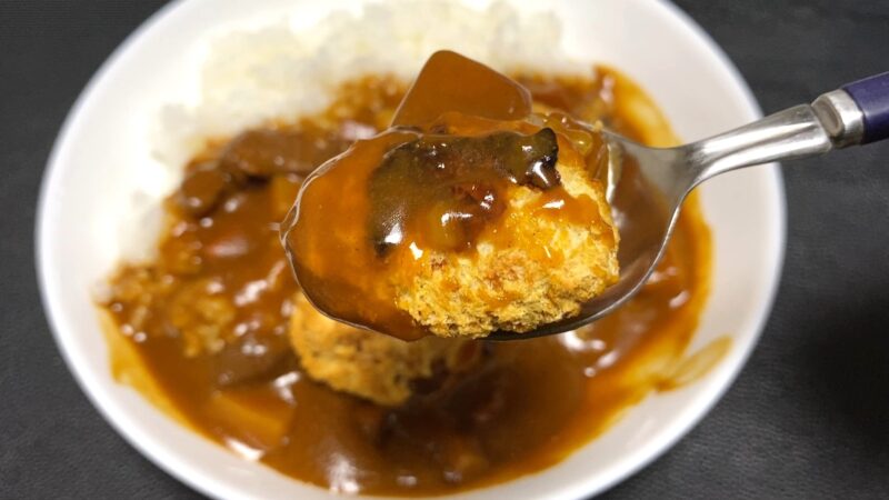 スプーンで持ち上げたチキンカツカレー。ルーがたっぷり絡んでいて、濃厚な香りが伝わる。