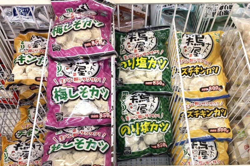 業務スーパーの冷凍食品コーナーに並ぶ「鶏屋さんのチキンカツ」シリーズ。 定番のチキンカツ、梅しそカツ、のり塩カツ、チーズチキンカツなどが並び、パッケージの色違いが目立つ売り場の様子。