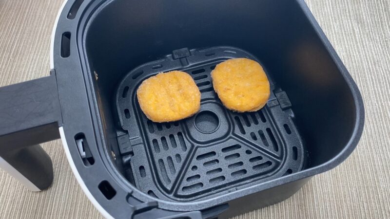 ノンフライヤーで加熱中のチキンナゲット。凍ったまま並べて加熱しており、油を使わずにサクッと仕上げられる調理方法。
