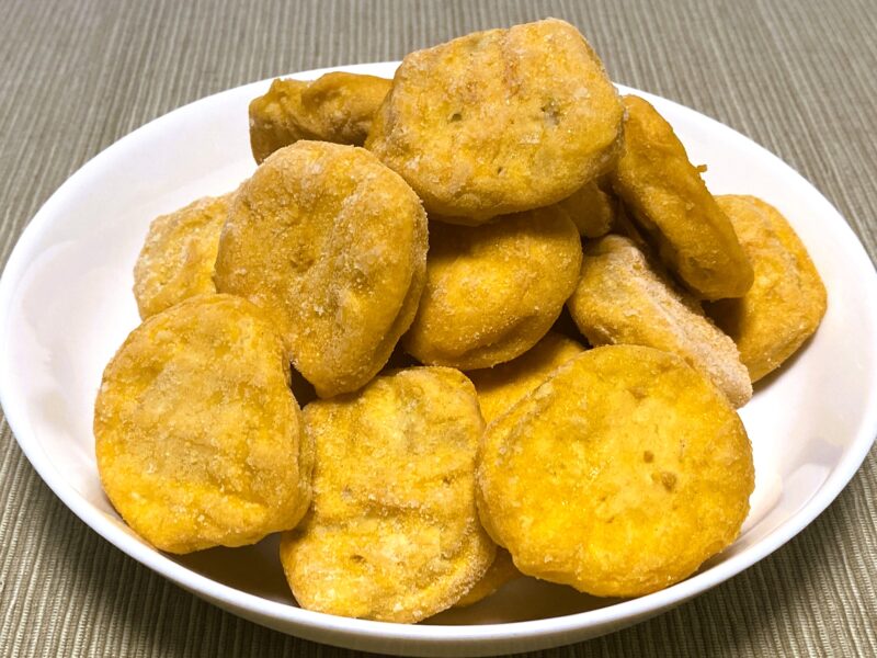 凍った状態のチキンナゲットを皿に盛った様子。衣は明るい黄色で、均一な形と厚みが特徴。