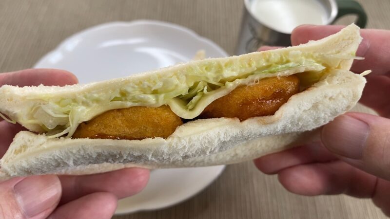 手に持ったチキンナゲットサンド。ふんわりしたパンの中に、キャベツとナゲットが並んでいる。