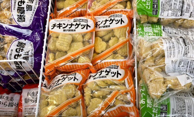 業務スーパーの冷凍食品売り場に並ぶチキンナゲット。オレンジ色の袋が目立つ。