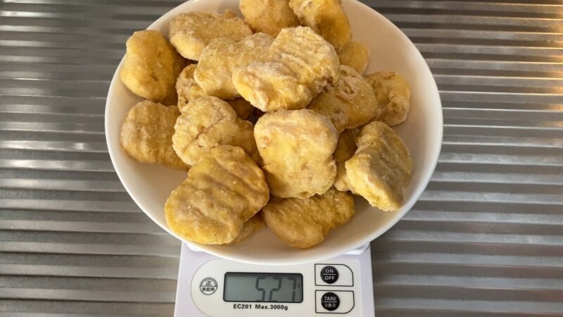 冷凍のチキンナゲットを皿に盛って計量した様子。527gと表示されている。