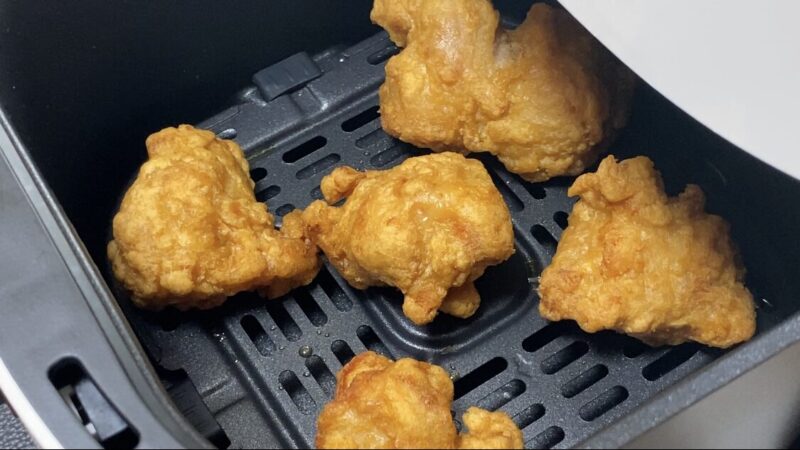 業務スーパーの和風鶏もも唐揚げをノンフライヤーに並べた調理中の様子。油を使わずにカリッと仕上げる工程が見える。