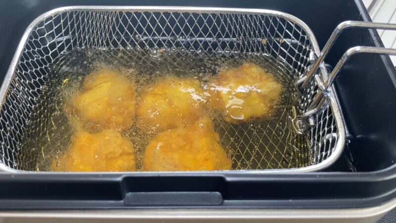 卓上フライヤーで業務スーパーの和風鶏もも唐揚げを油調理している最中の様子。油の泡が立ち、衣がきつね色に変わりつつある。