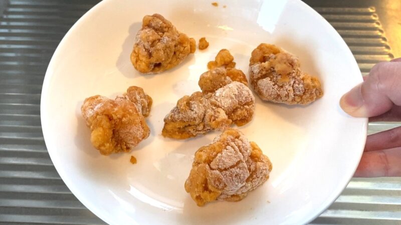 業務スーパーの和風鶏もも唐揚げを冷凍のまま皿に並べた状態。レンジ加熱前の工程で、衣には白く凍った粉が残っている。