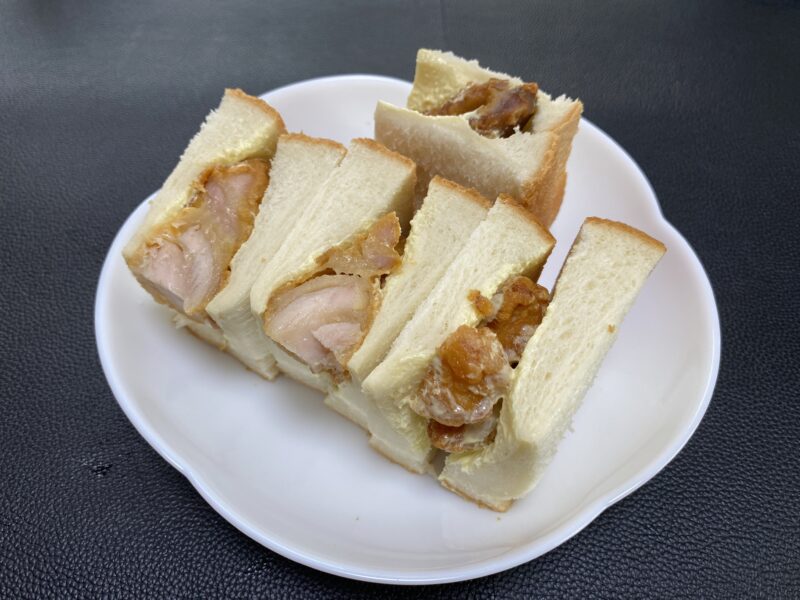 業務スーパーの和風鶏もも唐揚げをサンドした手作りサンドイッチ。ふんわりした食パンで挟まれ、断面からジューシーな唐揚げが見えている。