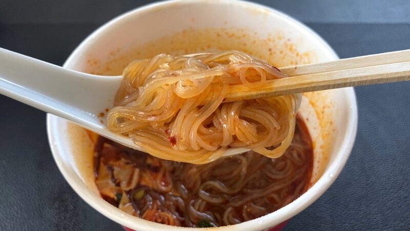 箸で持ち上げた酸辣粉（サンラーフン）の春雨。ツルツルとした透明感のある麺にスープが絡んでいます。