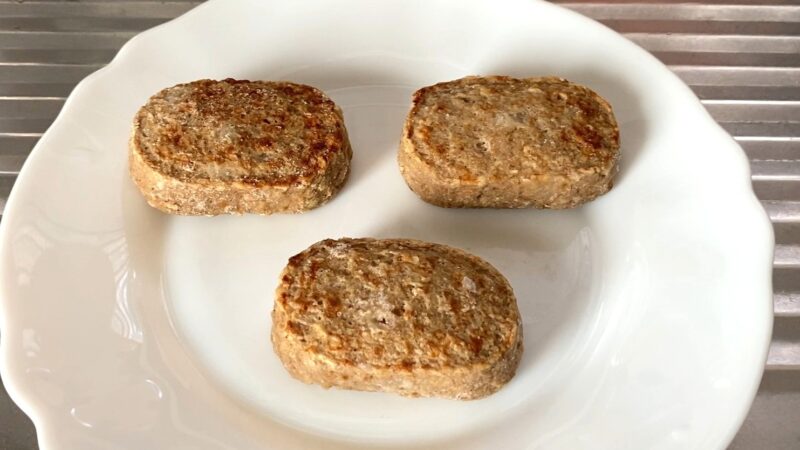 調理前の冷凍状態の焼上ミニハンバーグ。白っぽく霜がついており、冷凍ならではの硬さが見られます。