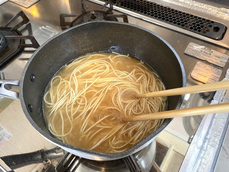 スープと一緒に麺を煮込んでいる途中の様子。箸でほぐしながら加熱中。