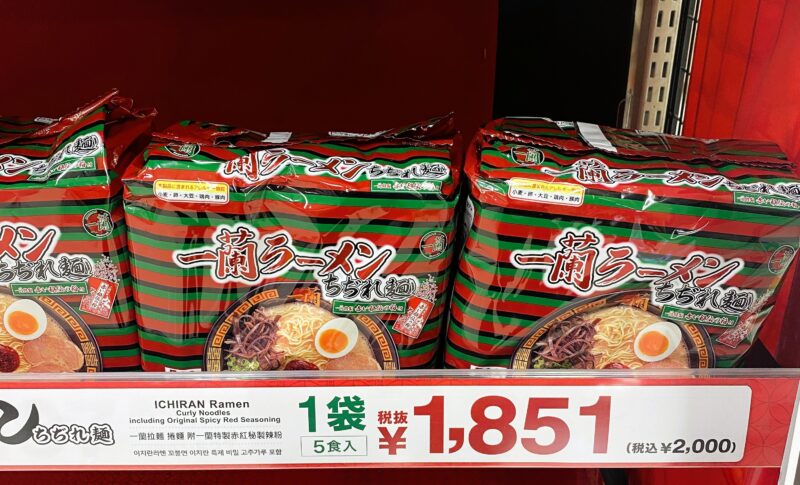 店頭に並ぶ一蘭ラーメン「ちぢれ麺」5食入りパック。赤と緑のストライプ包装と価格表示1851円（税抜）。