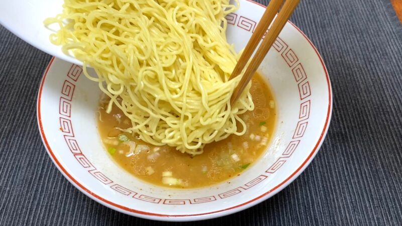 一蘭ラーメンの替え玉を丼へ追加している写真。茹でたての細麺を一気に投入する瞬間。
