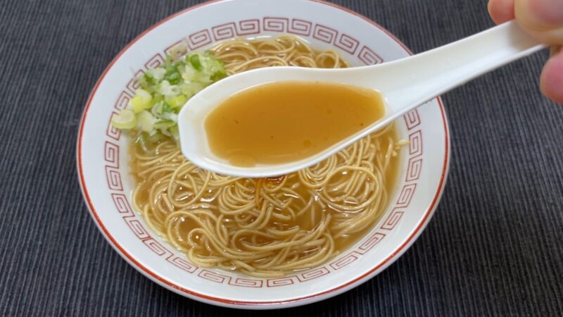 一蘭ラーメンのスープをレンゲですくった写真。秘伝の赤い粉を入れる前の状態で、透き通った豚骨スープの色合いが分かる。