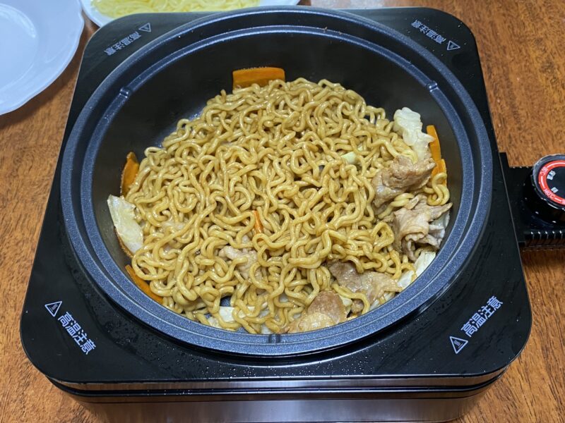 鍋プレートで調理した焼きそば。豚肉やキャベツ、にんじんが入り、テーブルの上で熱々のまま楽しめる一品。