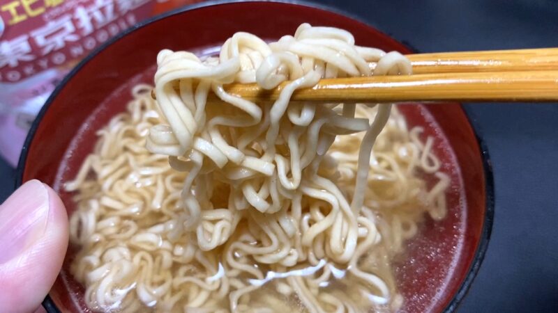 東京拉麺エビ塩トンコツ味の麺を箸で持ち上げたアップ写真。透き通ったスープが麺に絡み、あっさりとした質感が伝わる。