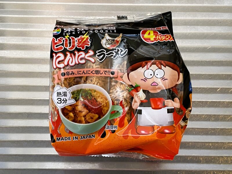 東京拉麺ピリ辛にんにく味のパッケージ。黒と赤のデザインで、唐辛子とにんにくを持ったキャラクターが描かれている。