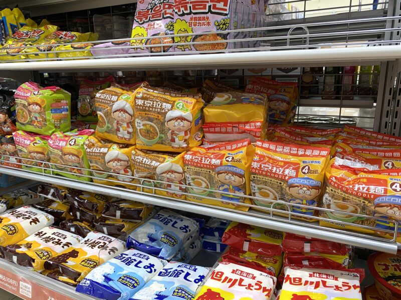 スーパーの棚に並ぶ東京拉麺シリーズ。黄色・茶色・緑のパッケージがぎっしりと陳列されている様子。