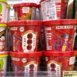 業務スーパーの店頭に並ぶ酸辣粉（サンラーフン）のカップ麺。赤いパッケージが目を引き、隣には白い酸湯面叶も陳列されています。