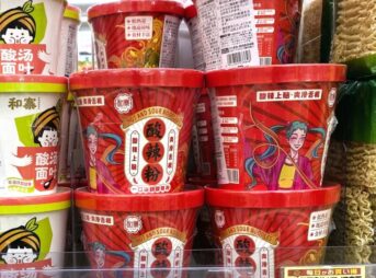 業務スーパーの店頭に並ぶ酸辣粉（サンラーフン）のカップ麺。赤いパッケージが目を引き、隣には白い酸湯面叶も陳列されています。