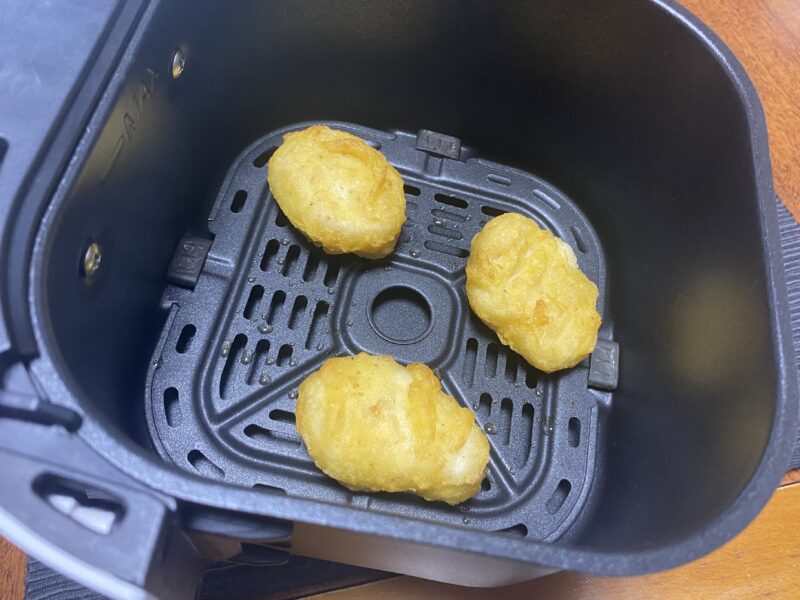 ノンフライヤーのバスケット内でチキンナゲットを調理している様子。衣がパリッと仕上がり、表面にツヤがある。