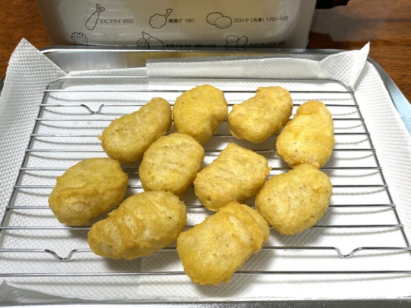 揚げたての業務スーパー「チキンナゲット（タイ産）」を網の上で油を切っている様子。衣がきつね色に仕上がり、サクサク感が伝わる。
