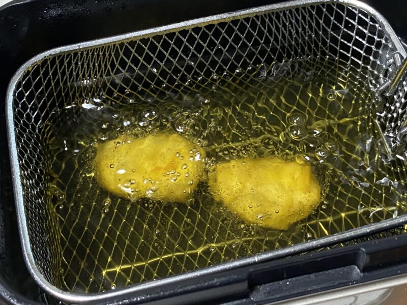 フライヤーで業務スーパーのチキンナゲット（タイ産）を揚げている様子。油の中で泡が立ち、ナゲットがきつね色に色づいていく。