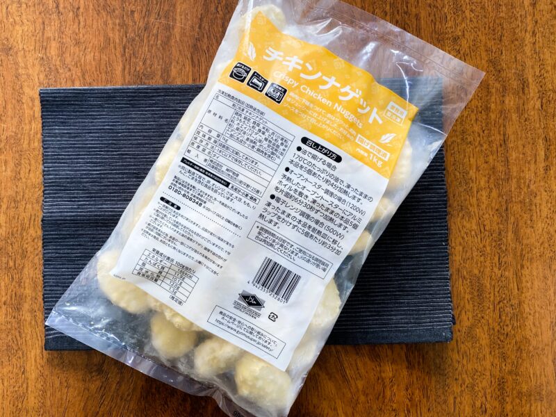 業務スーパーの「チキンナゲット（タイ産）」1kgパッケージを斜めから撮影した写真。袋の厚みや冷凍状態のナゲットが透けて見える。