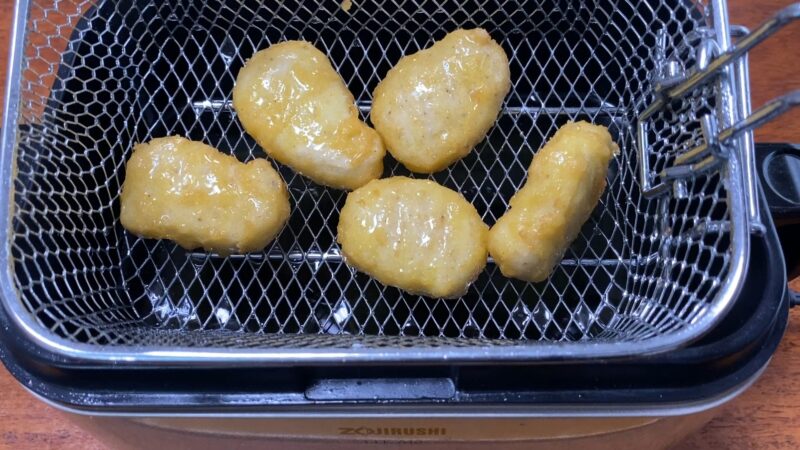 象印の家庭用フライヤーでチキンナゲットを揚げている様子。油の中で衣が色づき始めている。