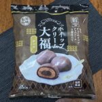 業務スーパー「ホイップクリーム大福（チョコ）」のパッケージ。黒いランチョンマットの上に置かれており、自然解凍・３層仕立ての説明が見える。