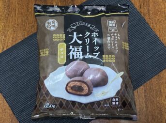 業務スーパー「ホイップクリーム大福（チョコ）」のパッケージ。黒いランチョンマットの上に置かれており、自然解凍・３層仕立ての説明が見える。