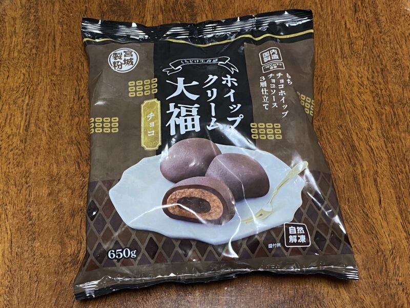 業務スーパー「ホイップクリーム大福(チョコ)」のパッケージ。木目調のテーブル上に置かれた状態で、内容量650gと記載がある。