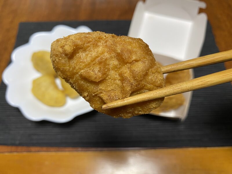 マクドナルドのチキンナゲットを箸で持ち上げた様子。濃いきつね色の衣が特徴