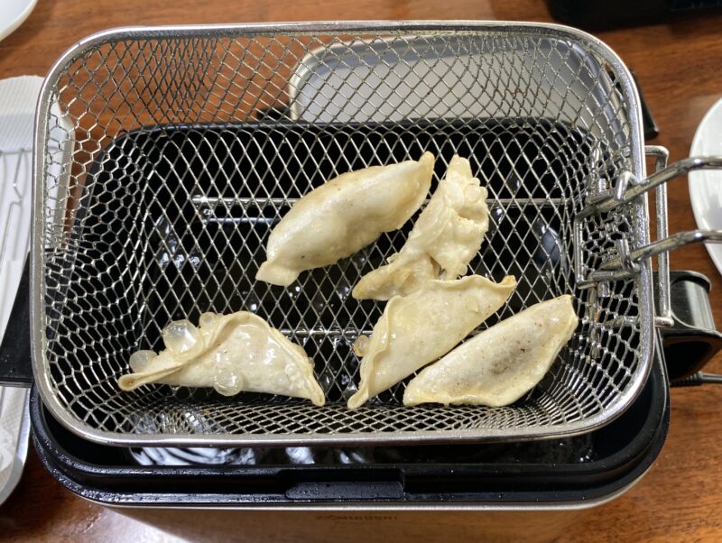 油で豚肉餃子を揚げている途中のバスケットの様子
