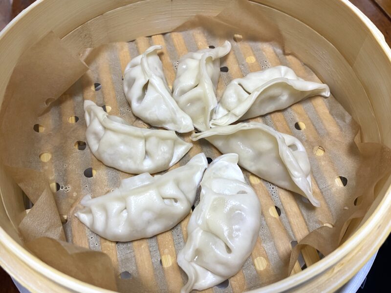 竹の蒸籠で豚肉餃子を並べて蒸している様子