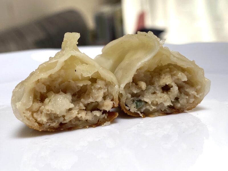 焼いた豚肉餃子を半分に切った断面の写真で、肉と野菜の餡がぎっしり詰まっている様子が見える。