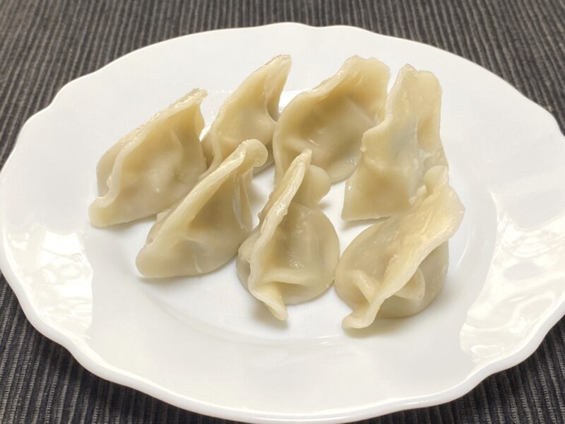 白い皿に盛り付けられた茹でた三鮮水餃子。皮がふっくら膨らみ、モチモチした質感が見える。