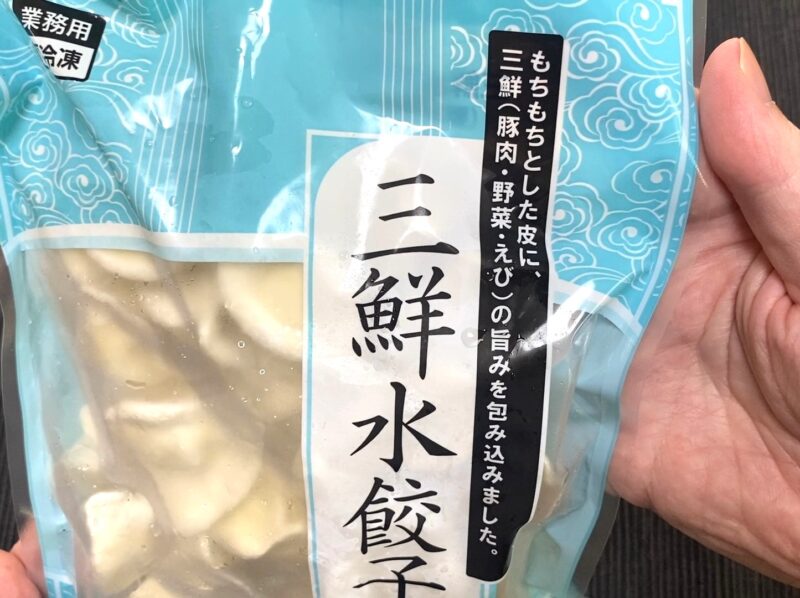 三鮮水餃子のパッケージを手に持ったアップ写真。「もちもちとした皮に三鮮(豚肉・野菜・えび)の旨み」と書かれている部分が見える。