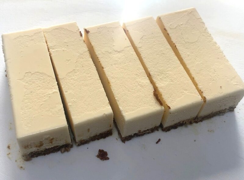 パッケージから取り出したカラメルカスタードを細長く均等にカットした様子。ムース層とスポンジ層の2段構造が分かる断面写真。