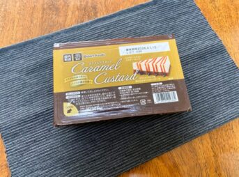 業務スーパーのカラメルカスタードのパッケージをテーブルの上に置いた様子。黄色と茶色のシンプルなパッケージが写っている。