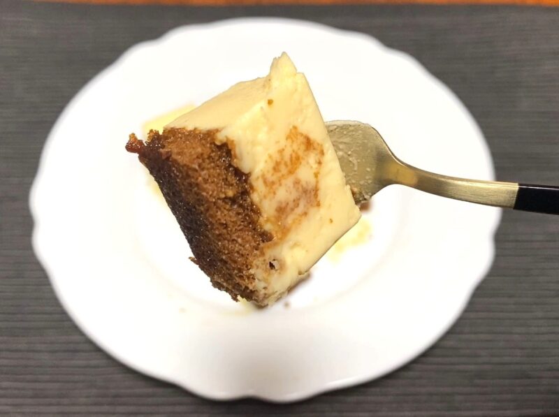 カラメルが染みたスポンジとカスタードムースを一口サイズに切り、フォークで持ち上げた様子。しっとりしたスポンジと滑らかなムースがよく分かるアップ写真。