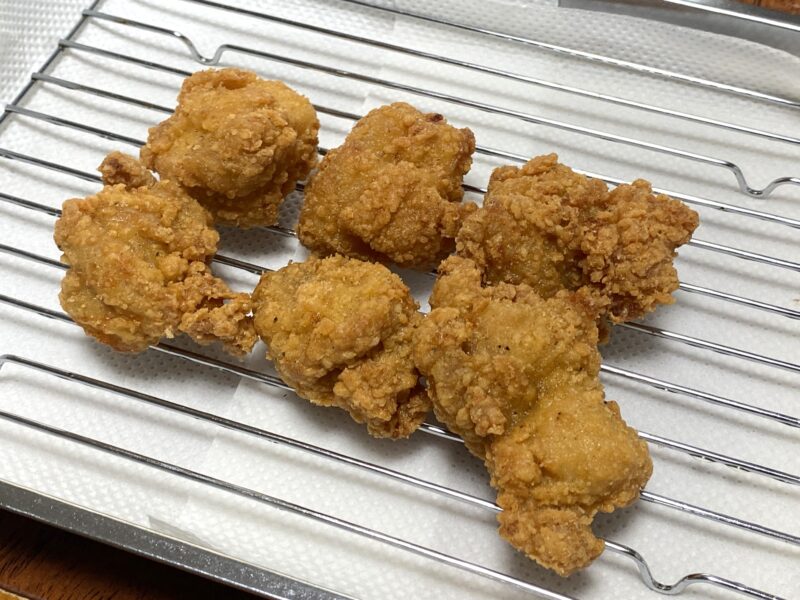 油調理した唐揚げをバットと網の上で油切りしている様子。衣がカリッと揚がり、色づきも良い状態。