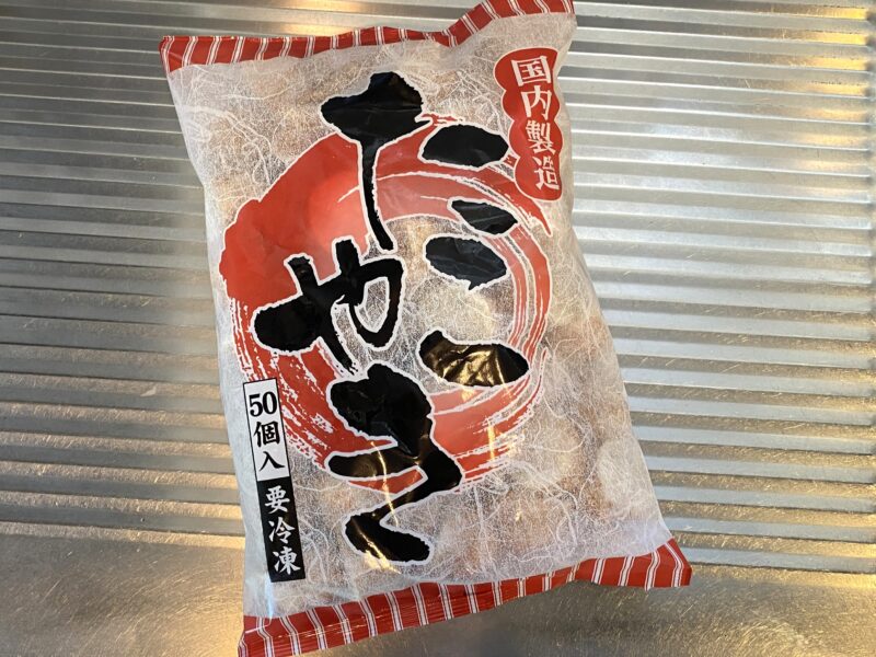 国内製造の冷凍たこ焼き1kg(約50個入り)パッケージ。国産素材を使用した小ぶりサイズのたこ焼き商品がわかる外装写真。