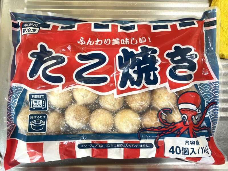 業務用の冷凍たこ焼き1kg(40個入り)パッケージ。もっちり食感のたこ焼きが特徴で、電子レンジや油調理に対応した大容量商品の外装写真。