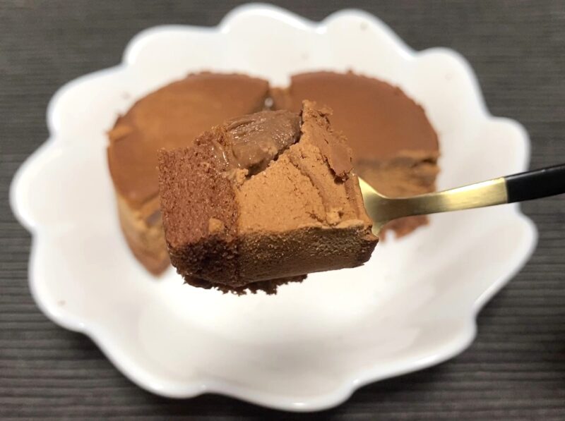 業務スーパー「ガトーショコラの誘惑」をフォークですくったひと口サイズの断面アップ。ガナッシュ、ムース、濃厚ショコラ、スポンジが重なるチョコの4重奏がはっきり見える画像